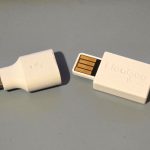 The FlooGoo FMA120 Auracast dongle next to a USB A to USB C converter