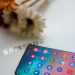 Samsung One UI 8 beta has launched. Picture shows a Samsung mobile phone on a Samsung laptop screen with some flowers in the background