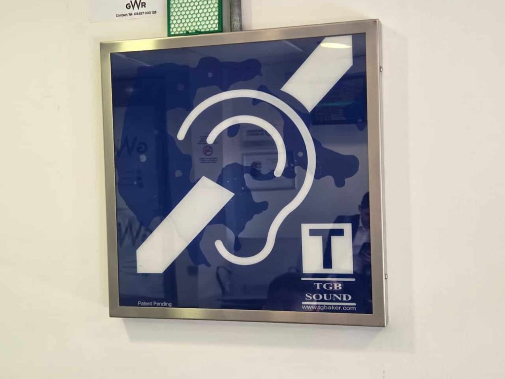 A sign denoting a Telecoil/loop in a railway waiting room. It is a symbol of an ear with a wire running through it, with a small T next to it