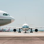 Two airplanes on a runway ready to take off at an unknown airport