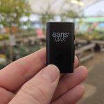 earisMAX Auracast streaming microphone held between finger and thumb in a garden centre