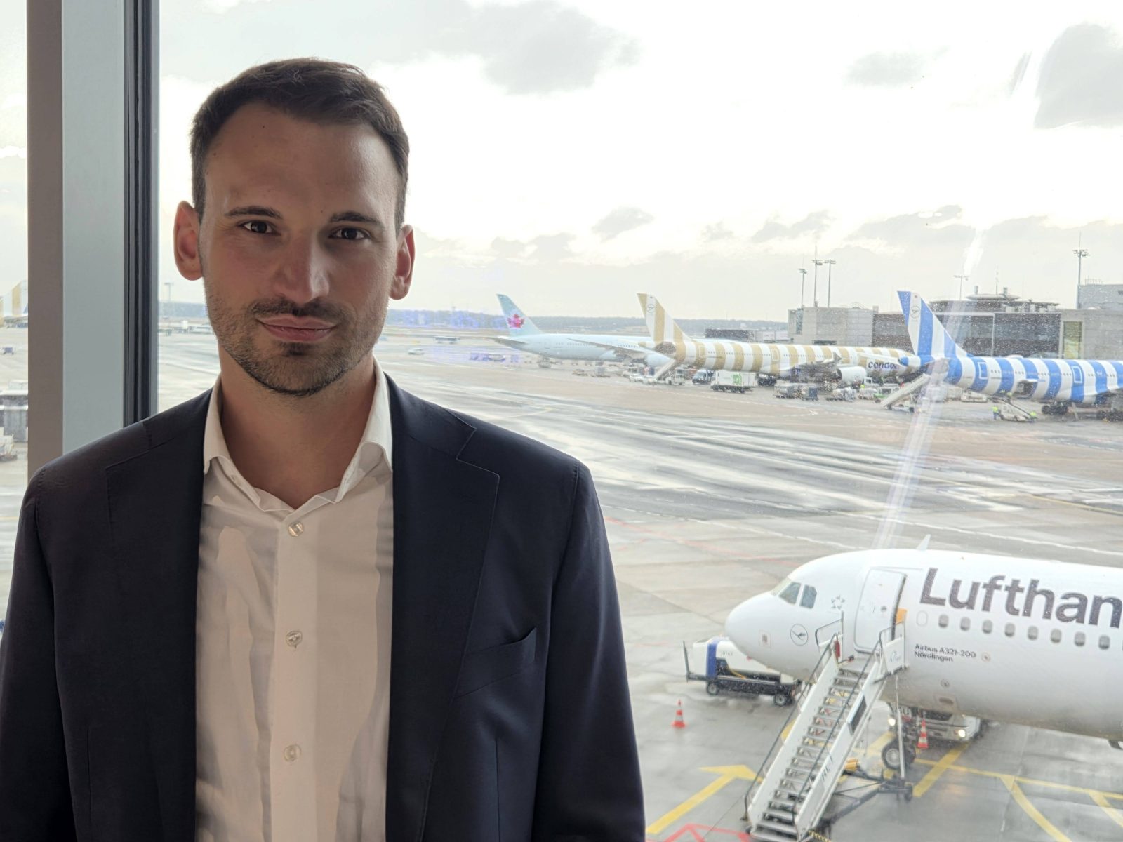 Johannes Sittig looking at the camera, with aeroplanes behind him