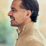 A head and shoulders of a man wearing a Cochlear; Auracast is now available for some models