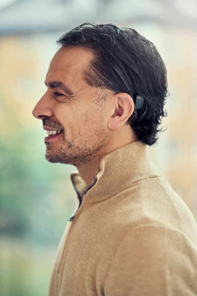 A head and shoulders of a man wearing a Cochlear; Auracast is now available for some models