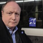 Phil Creighton on a bus with a Telecoil logo behind him