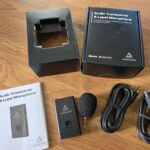 The Audeara Audio Transceiver and Lapel Microphone, cables and instructions taken from the box, which is above it