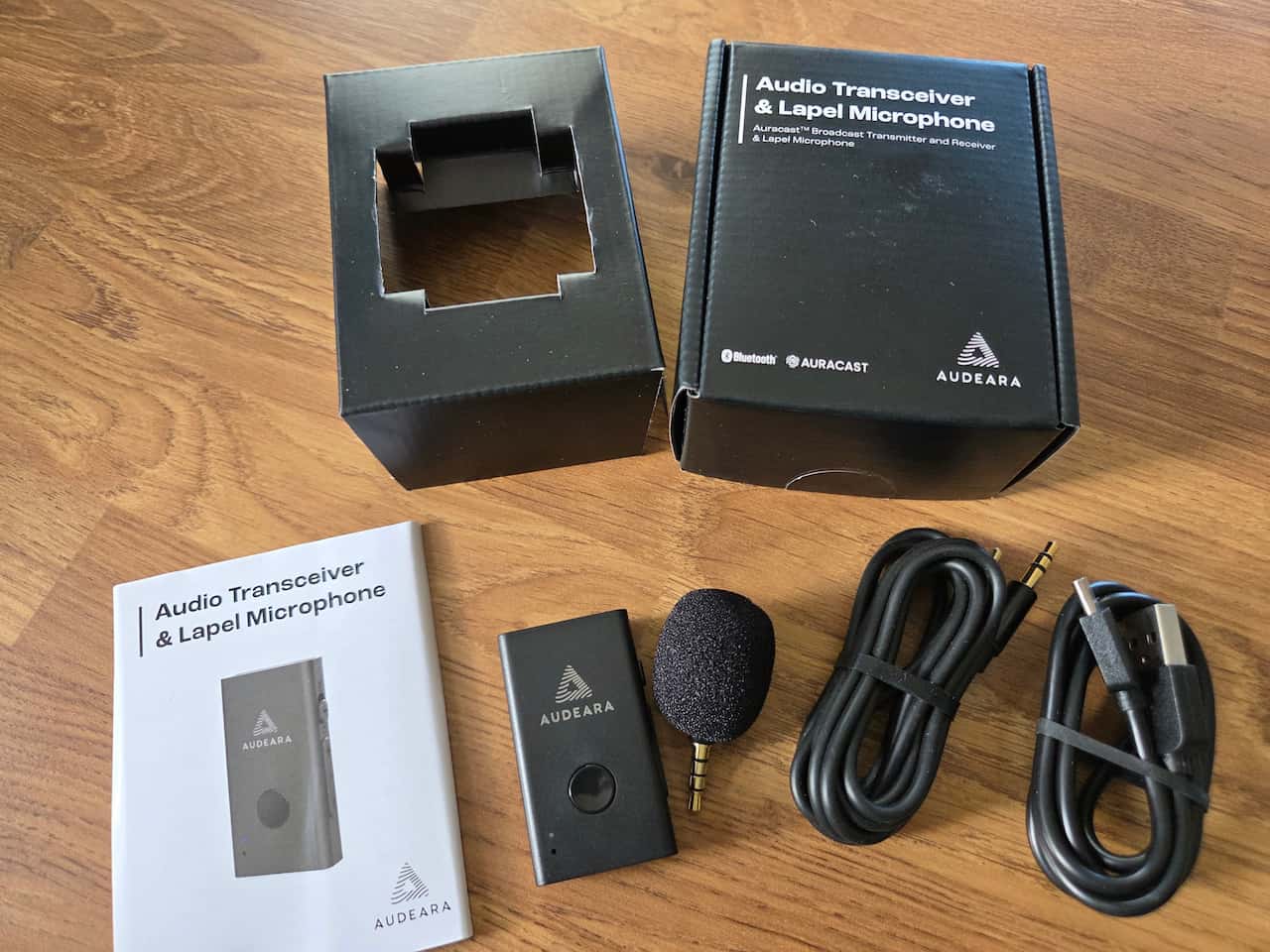The Audeara Audio Transceiver and Lapel Microphone, cables and instructions taken from the box, which is above it