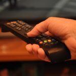 A person holding a television remote control