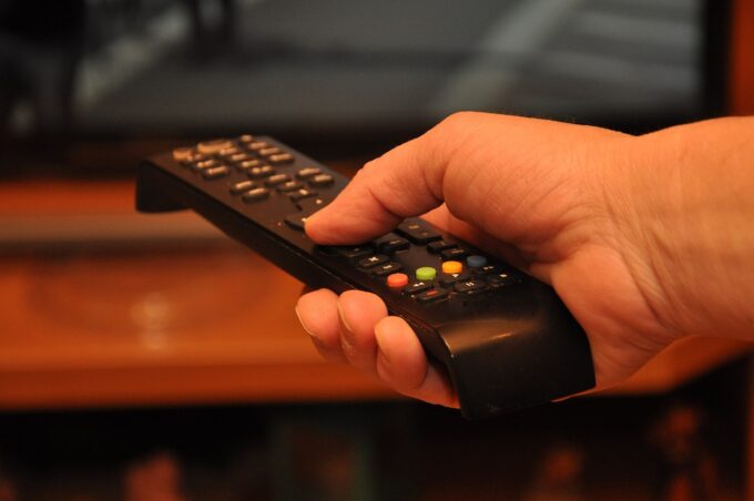 A person holding a television remote control