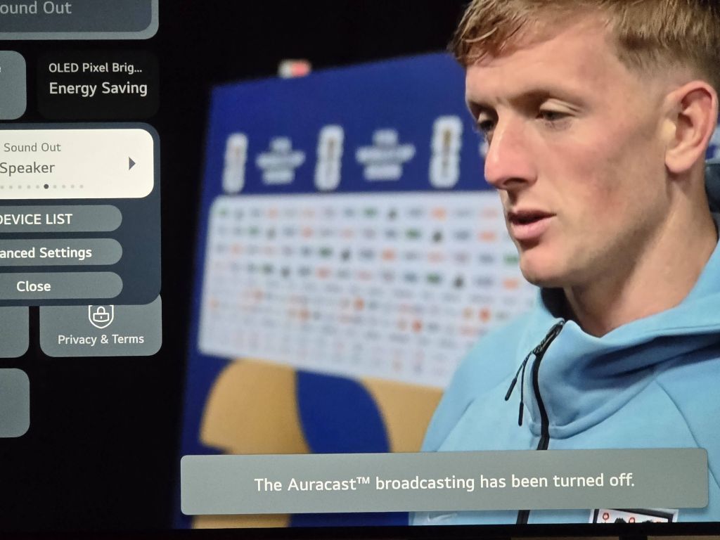 A television screen displaying an interview with a blonde England football player wearing a light blue hoodie. The webOS quick settings panel is open on the left showing Sound Out options, and a grey notification bar along the bottom reads, The Auracast™ broadcasting has been turned off.