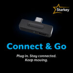 a promotional graphic on a solid black background. Centred in the upper half is a small, rectangular black wireless adapter device with a USB-C connector extending from the top edge. In the top right corner is the Starkey logo, consisting of a yellow outline of a star next to the company name in white text. Below the device, large blue text reads Connect and Go, followed by smaller white text that says Plug in. Stay connected. Keep moving.