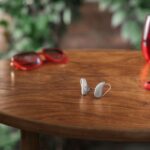 A pair of silver Signia Pure C&G MaX receiver-in-canal hearing aids standing on a round wooden table next to a smartphone