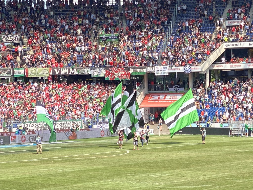 Flags being waved on the pitch while thousands of fans cheer