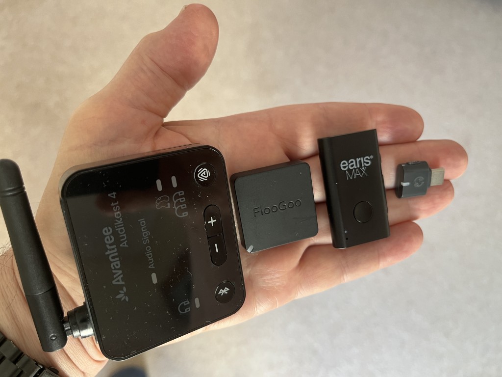 ALT Text: A hand holds four small black electronic devices: